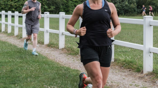 On a run next to a white picket fence and green grass